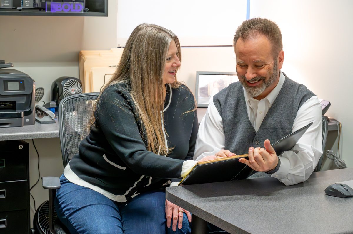 Jeff and Michelle Guykema of HeartLink Homes reviewing a client binder together at their office desk